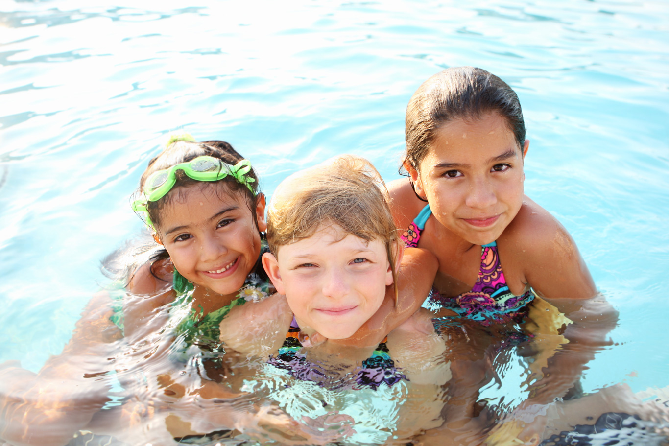three kids smiling in a pool